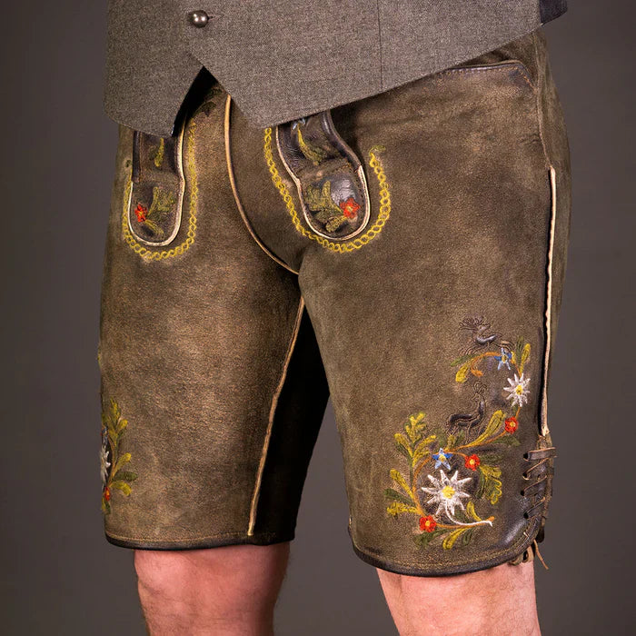 Moderner bayerischer Mann trĂ€gt eine kurze Wildbock Lederhose aus hochwertigem Wildleder mit feinen Reliefstickereien, kombiniert mit einem weiĂen Trachtenhemd â Datschi Trachten Kollektion